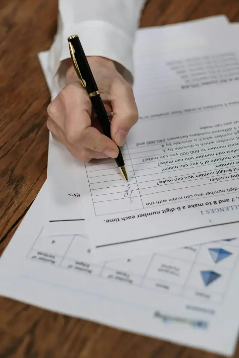 Person filling out a financial form with a pen