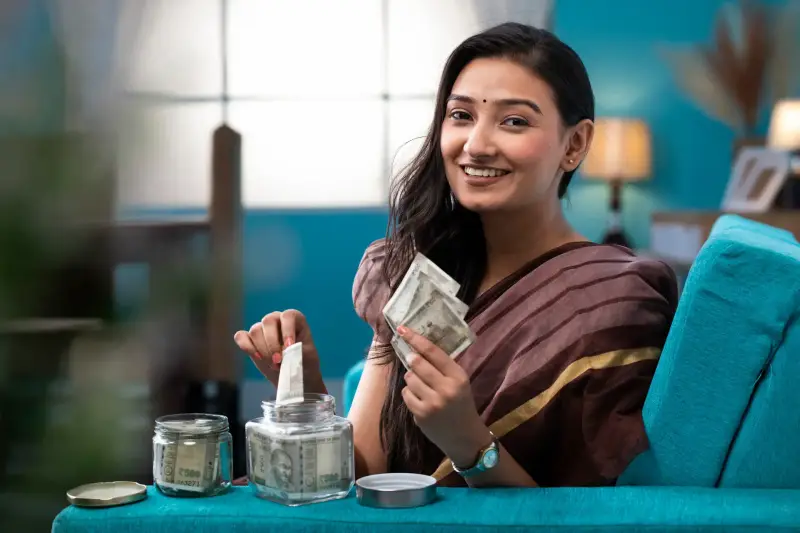 Woman saving money systematically in a glass jar